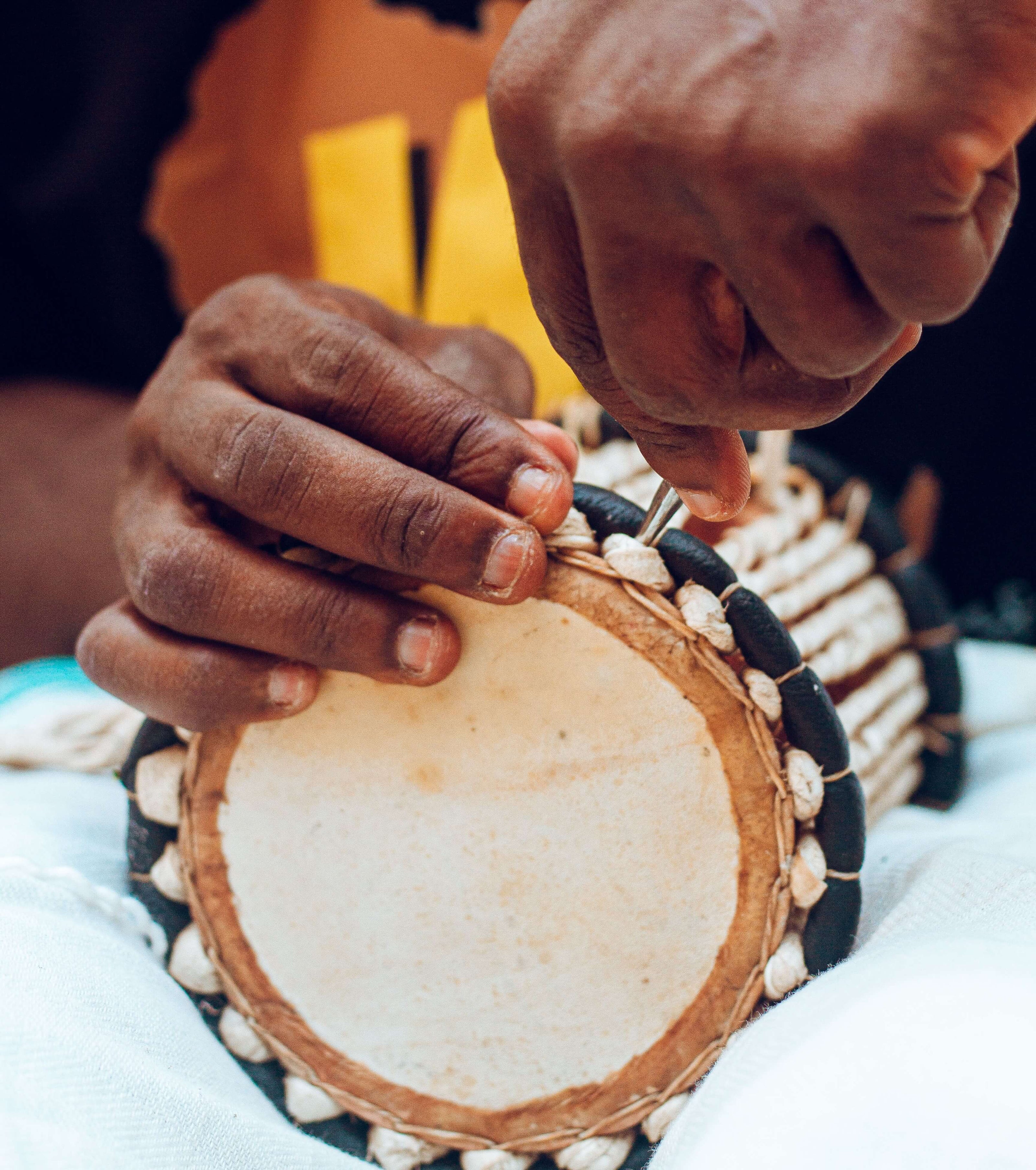 Close-up of hands fixing a traditional drum.